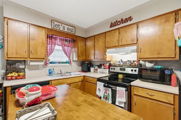 a kitchen with stainless steel appliances a sink dishwasher stove and cabinets with wooden floor