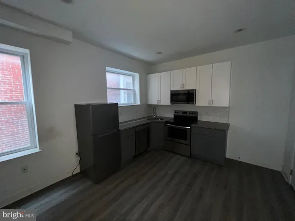 a kitchen with granite countertop a refrigerator and a stove top oven