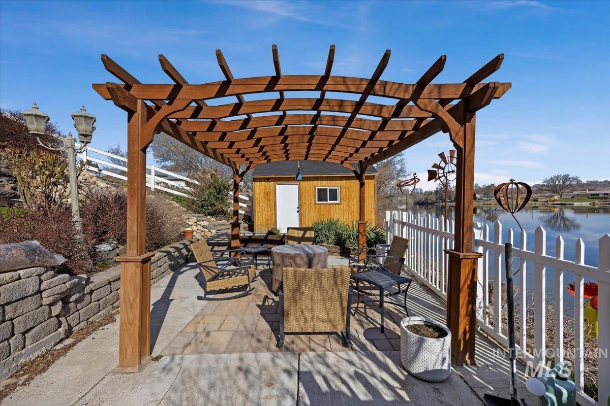 40 Bell Rapids Road Hagerman, ID 83332 - Photo 39 of 50 View of patio featuring outdoor dining space, a water view, a pergola, and a storage unit