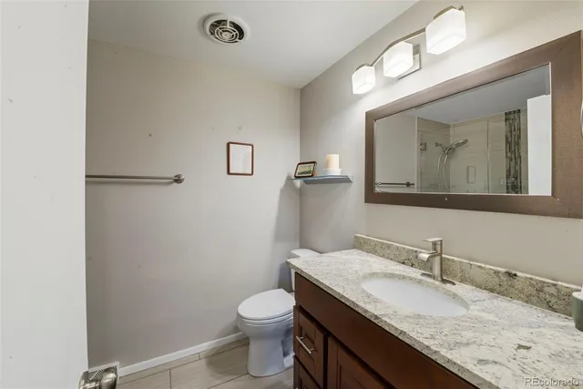 a bathroom with a granite countertop sink mirror vanity and toilet