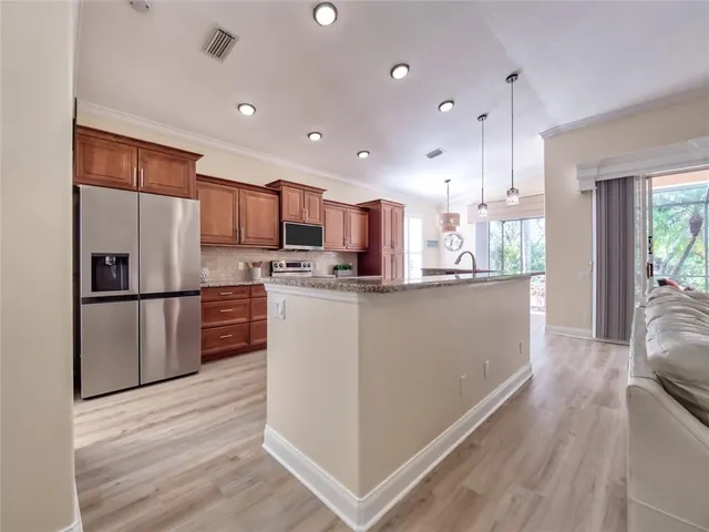 a kitchen with granite countertop wooden cabinets stainless steel appliances and a window