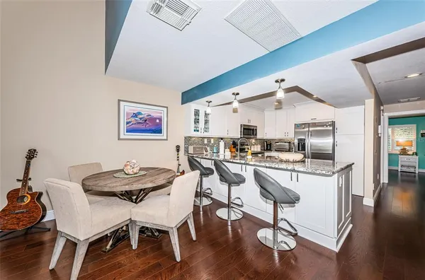 a kitchen with a dining table chairs and wooden floor