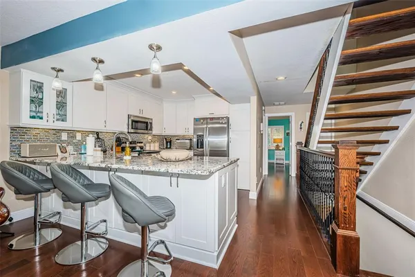 a kitchen with granite countertop kitchen island wooden floors and stainless steel appliances