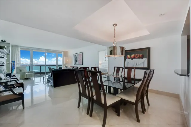 a view of a dining room and livingroom with furniture a rug a chandelier and a window