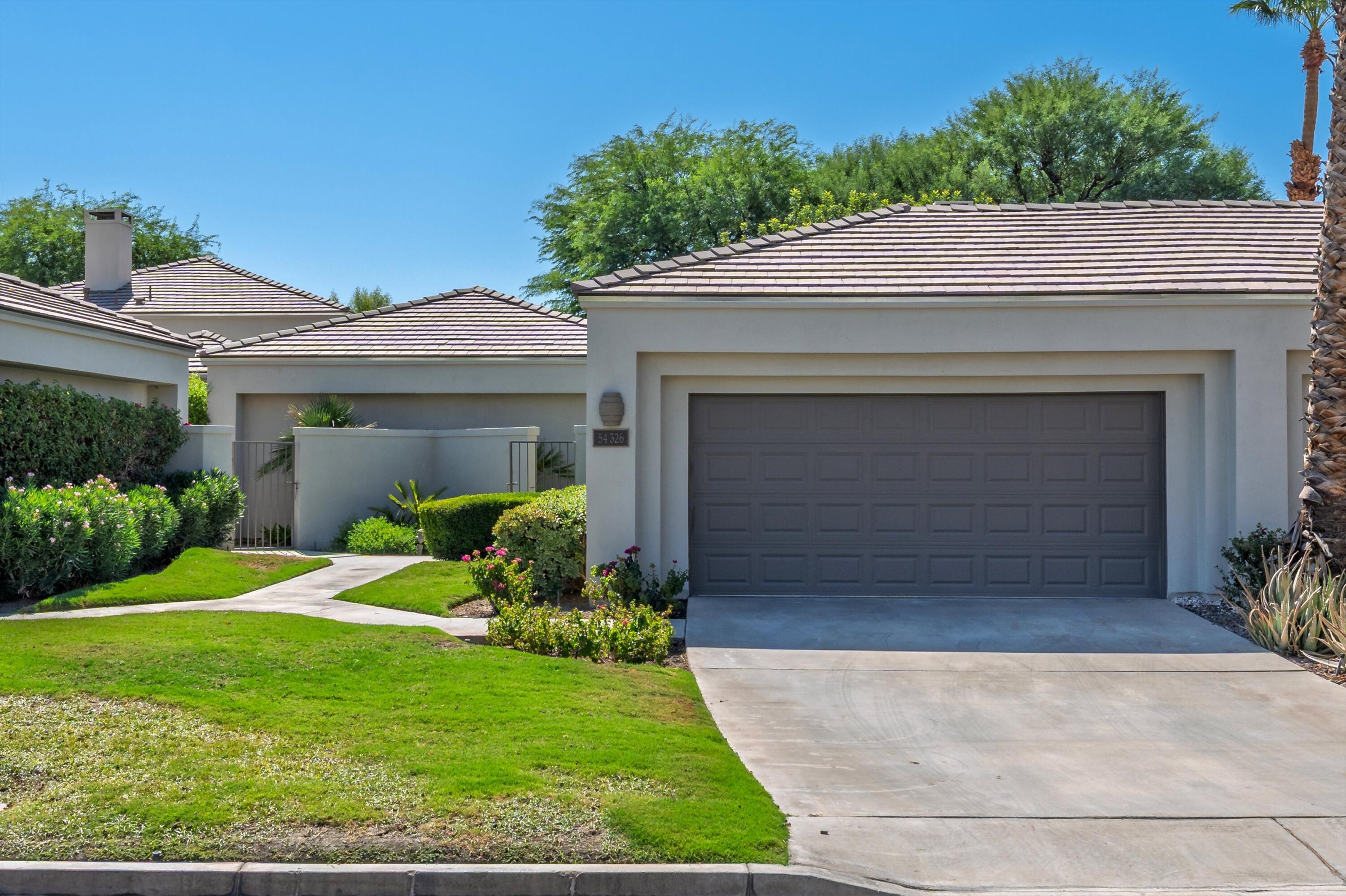 54326 Oak-Tree, Unit A122 La Quinta, CA 92253 - Photo 28 of 32 a front view of a house with a yard and garage