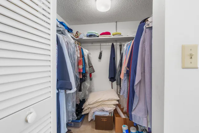a view of walk in closet with clothes and shoes