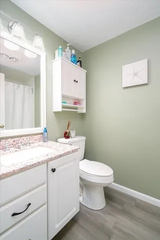 a bathroom with a granite countertop toilet sink and mirror