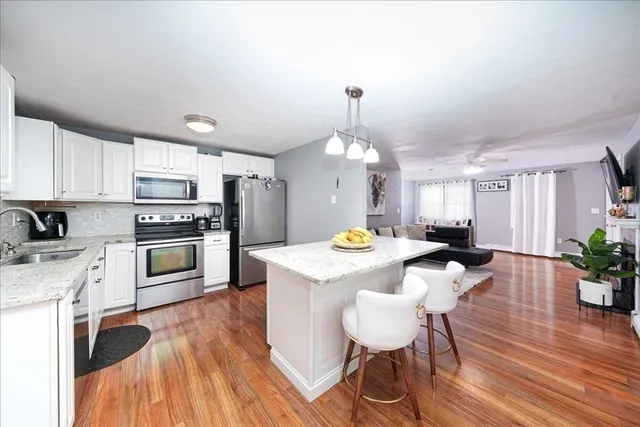 a view of a kitchen counter space a sink dishwasher a dining table and chairs with wooden floor