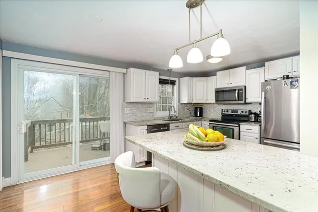 a kitchen with stainless steel appliances granite countertop a stove a refrigerator a sink a microwave oven with a dining table and chairs