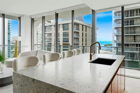 a living room with furniture kitchen view and a large window