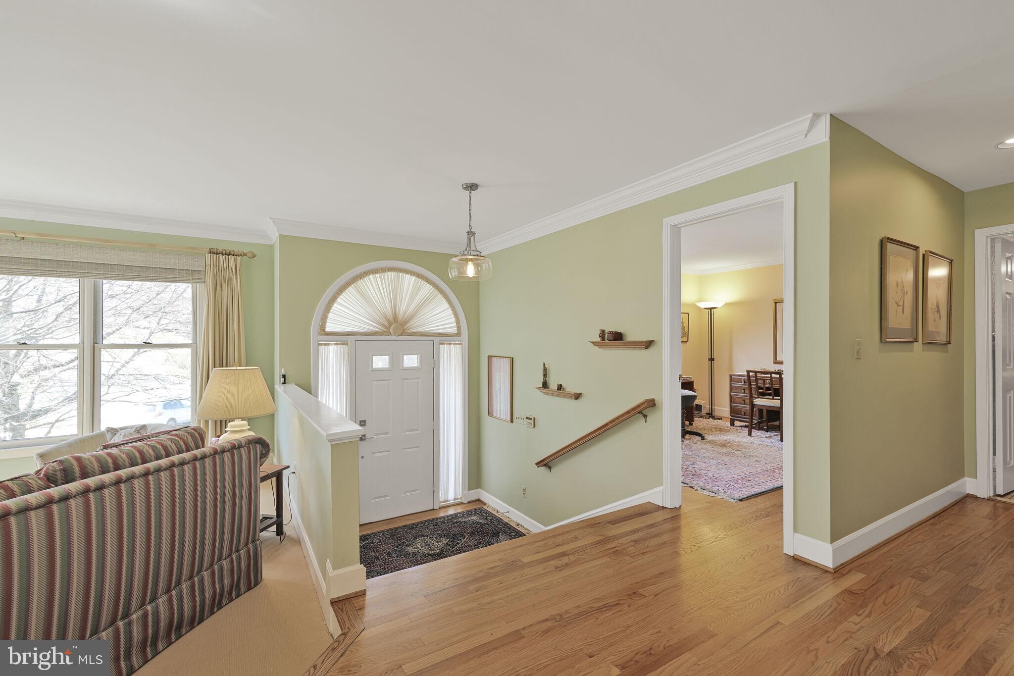 9501 Columbia Boulevard Silver Spring, MD 20910 - Photo 3 of 32 a view of a hallway to a livingroom with furniture wooden floor mirror and a window