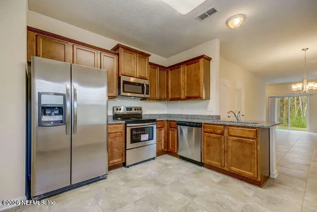 a kitchen with stainless steel appliances granite countertop a refrigerator a stove a sink and a microwave