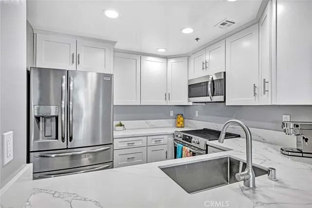 a kitchen with stainless steel appliances granite countertop a refrigerator sink and white cabinets