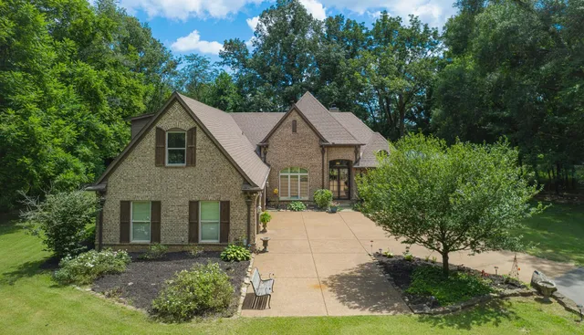 a front view of a house with a yard and trees