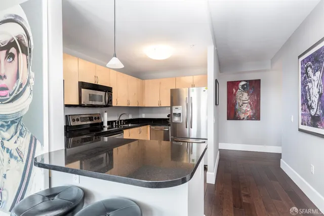 a kitchen with stainless steel appliances granite countertop a sink a stove and a refrigerator with wooden floor