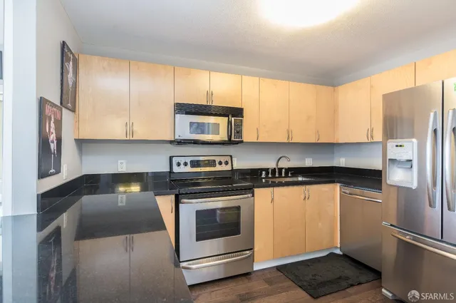 a kitchen with stainless steel appliances granite countertop a stove a sink and a refrigerator with cabinets