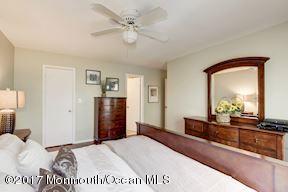 21 Maple Lane, Unit B Brielle, NJ 08730 - Photo 25 of 51 a spacious bedroom with a large bed and a chandelier
