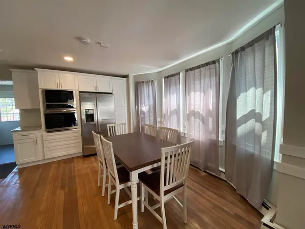 a kitchen with stainless steel appliances wooden floor dining table and chairs