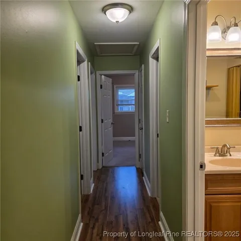 a view of a hallway with wooden floor and a bathroom