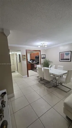 a living room with patio furniture and a dining table with kitchen view