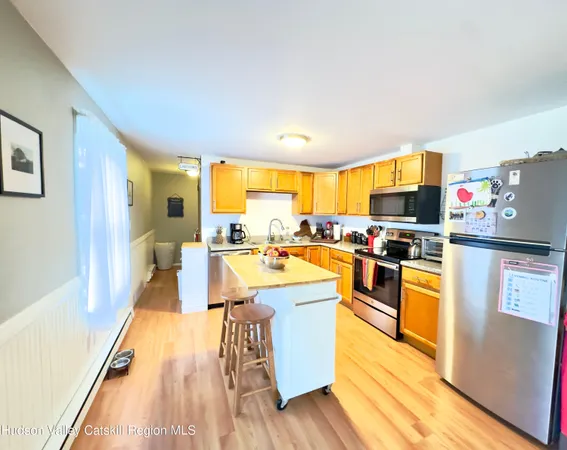 a large kitchen with stainless steel appliances a stove a refrigerator a sink dishwasher and a dining table with wooden floor