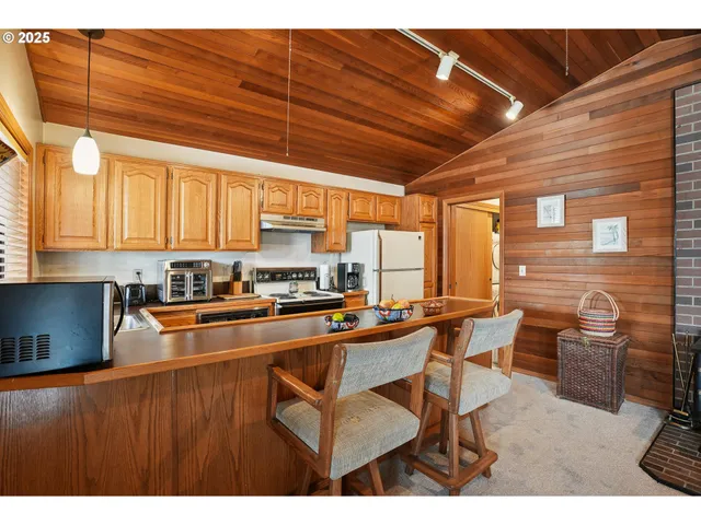 a open kitchen with stainless steel appliances kitchen island granite countertop a table chairs and a refrigerator