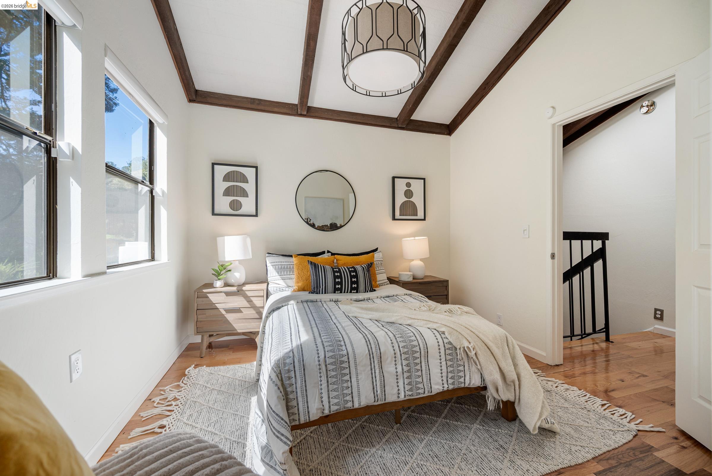 6600 Heather Ridge Way Oakland, CA 94611 - Photo 29 of 66 Vaulted white ceilings with exposed wood beams define this room, complemented by wood-finish flooring