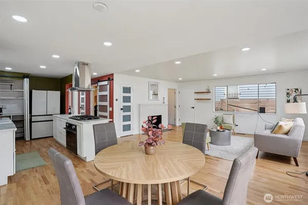 a living room with stainless steel appliances furniture a dining table and kitchen view