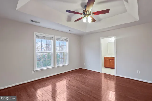 an empty room with wooden floor fan and windows