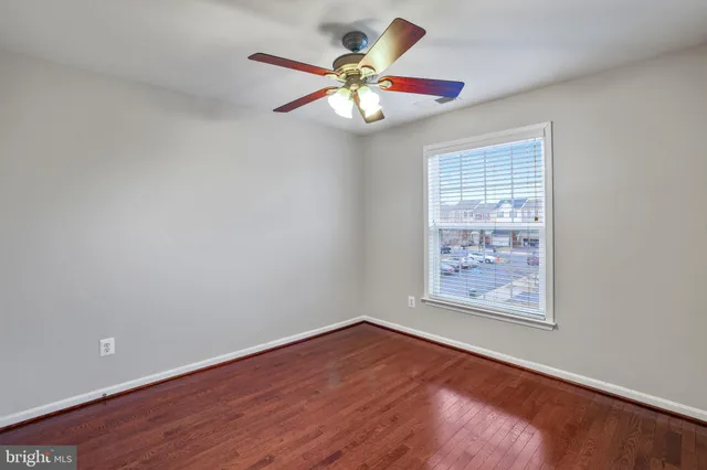 an empty room with wooden floor and ceiling fan