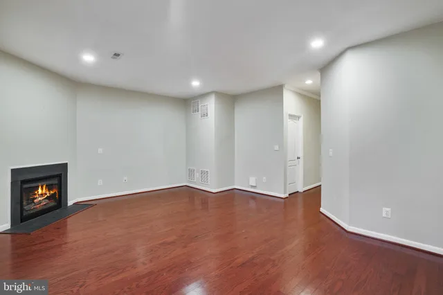 an empty room with wooden floor and a fireplace
