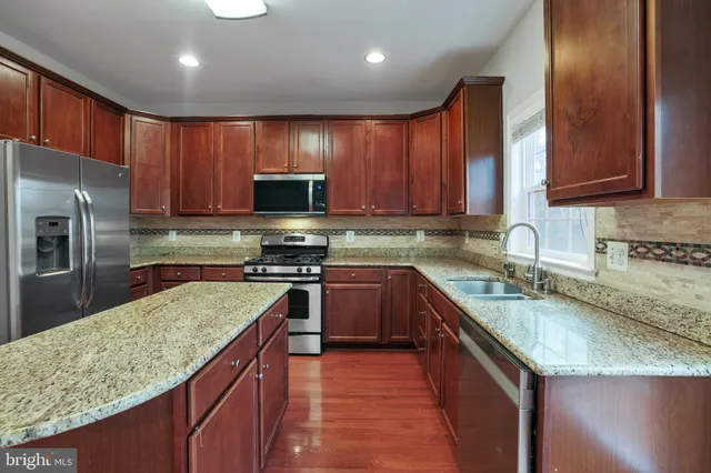 a kitchen with stainless steel appliances granite countertop a sink stove microwave refrigerator and cabinets