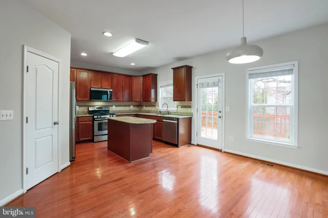 a large kitchen with stainless steel appliances granite countertop a stove a sink dishwasher a refrigerator and a oven with wooden floor