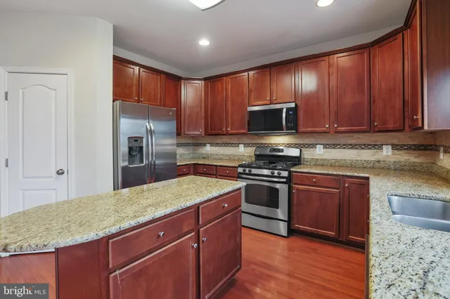 a kitchen with stainless steel appliances granite countertop wooden cabinets a stove a sink and a granite counter top