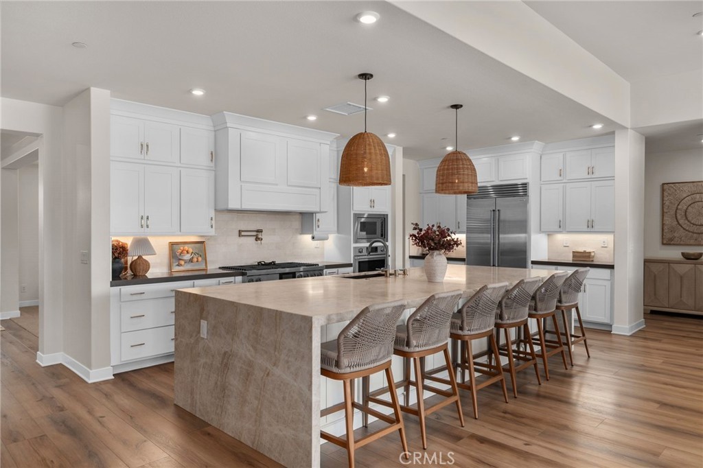 16155 New Canaan Court Riverside, CA 92504 - Photo 7 of 26 a kitchen with stainless steel appliances granite countertop a stove a sink dishwasher a dining table and chairs with wooden floor