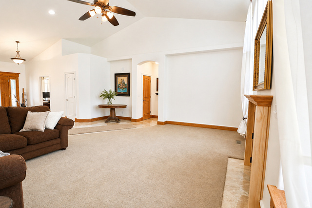 1055 North 1000 East Mapleton, UT 84664 - Photo 23 of 112 Spacious living area featuring vaulted ceilings with a ceiling fan, carpet flooring, a stone hearth, and natural wood trim throughout
