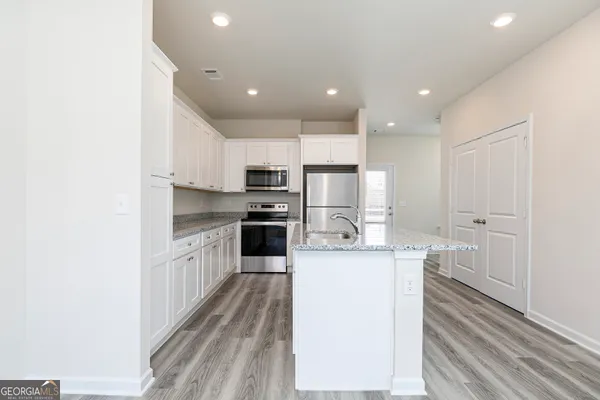 a kitchen with stainless steel appliances kitchen island granite countertop a refrigerator and a stove top oven