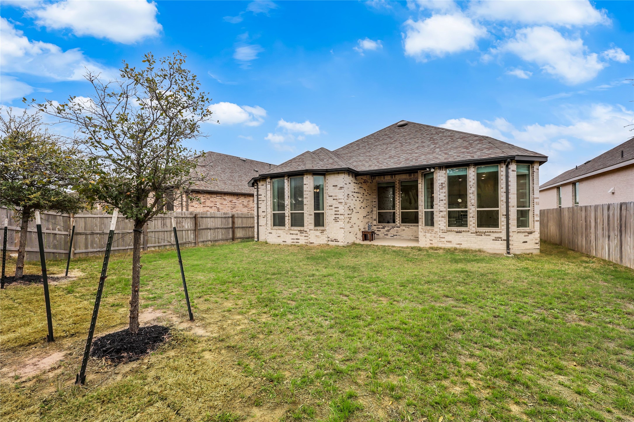 7705 Pace Ravine Drive Lago Vista, TX 78645 - Photo 26 of 40 Rear view of property featuring brick siding, a patio, a fenced backyard, and a shingled roof