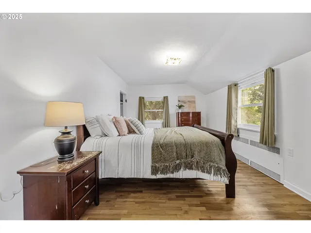 a spacious bedroom with a bed and wooden floor