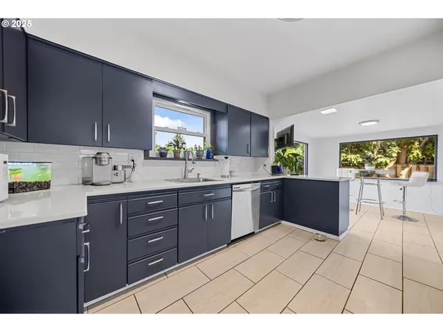 a kitchen with stainless steel appliances a sink a stove a refrigerator cabinets and a window