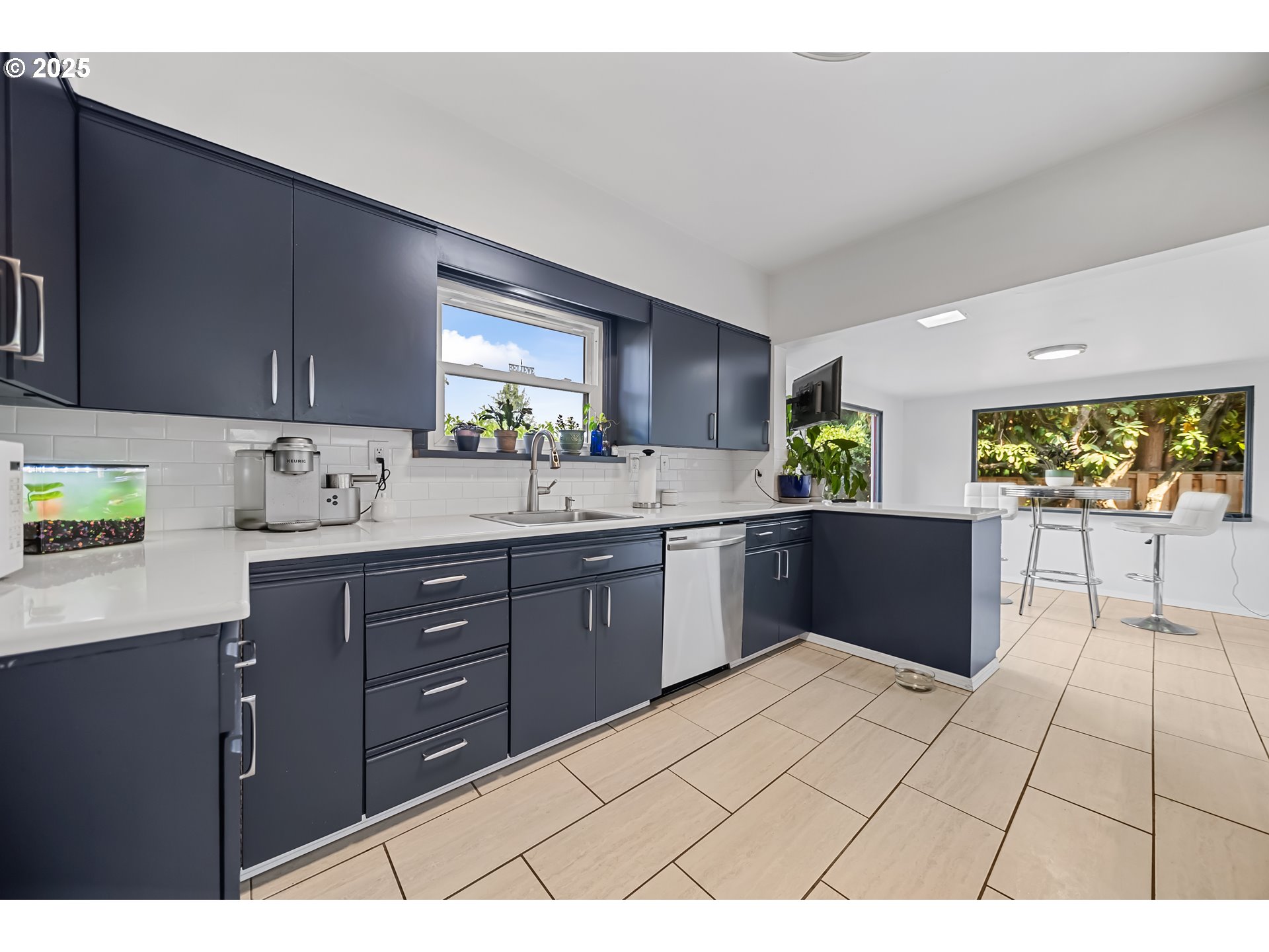 6026 Northeast 57th Avenue Portland, OR 97218 - Photo 9 of 45 a kitchen with stainless steel appliances a sink a stove a refrigerator cabinets and a window