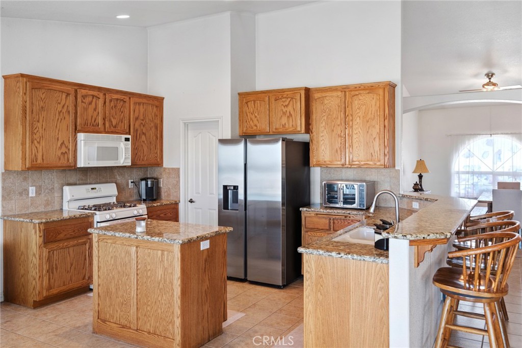 11025 El Esteban Road Phelan, CA 92371 - Photo 14 of 54 a kitchen with stainless steel appliances granite countertop a stove top oven a refrigerator a sink and dishwasher with wooden floor