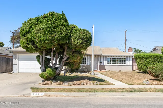 a front view of a house with a yard and potted plants