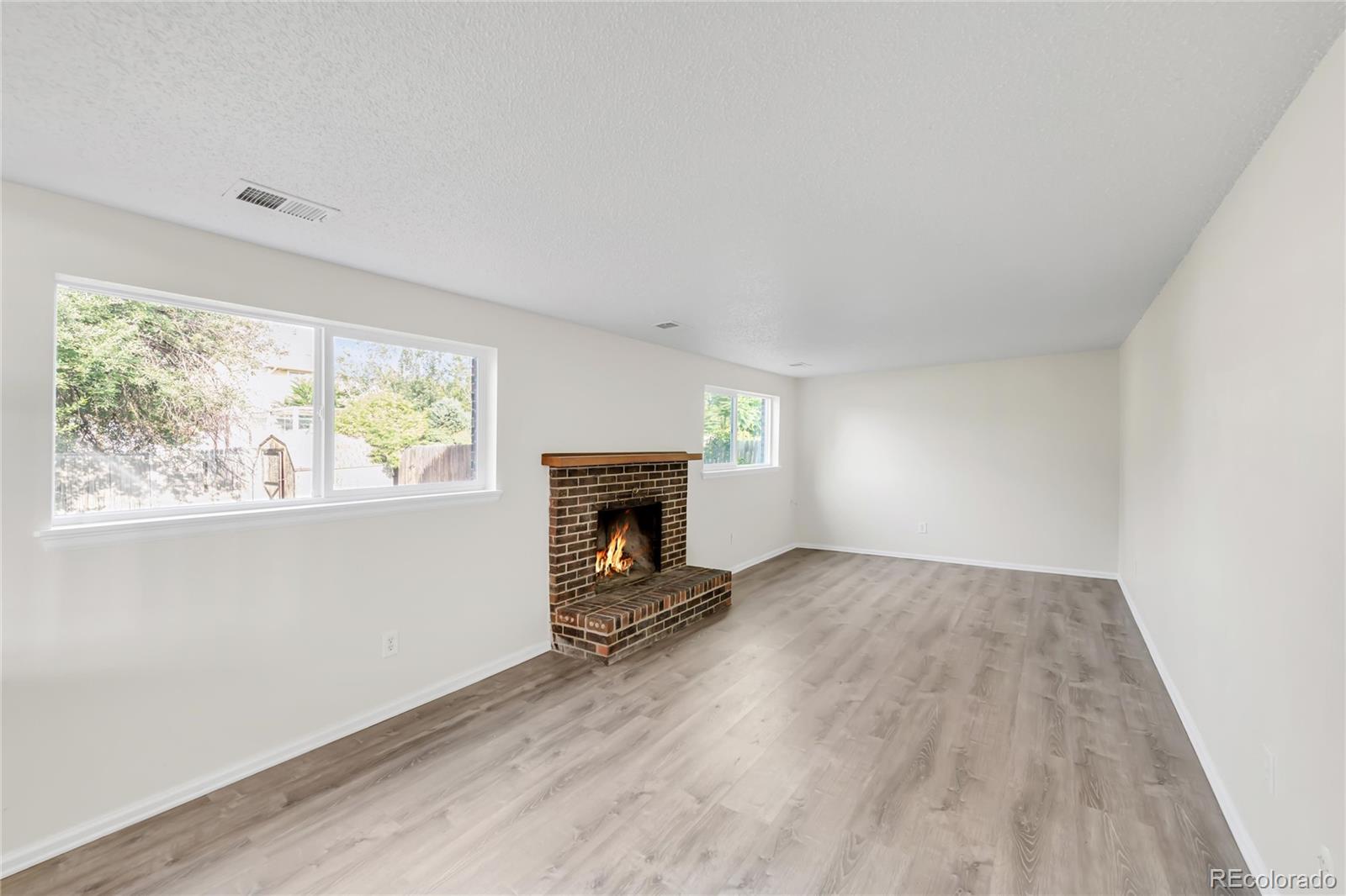 9215 Lowell Boulevard Westminster, CO 80031 - Photo 11 of 30 an empty room with windows a fireplace and wooden floor
