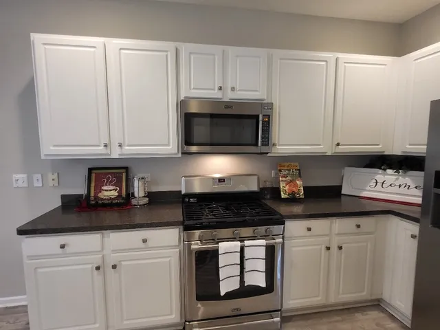 a stove top oven sitting inside of a kitchen and white cabinets