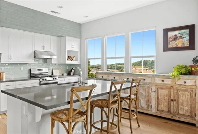 a kitchen with stainless steel appliances granite countertop a table chairs sink refrigerator and cabinets