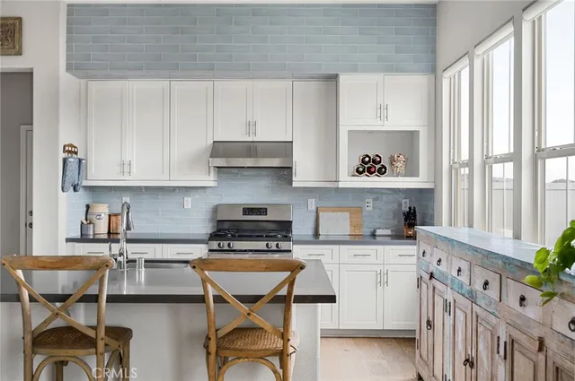 a kitchen with stainless steel appliances kitchen island granite countertop a table chairs in it and wooden floors