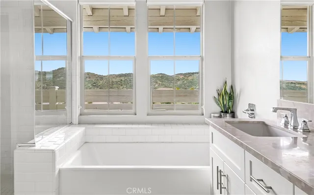 a bathroom with a granite countertop sink and a large mirror next to a window