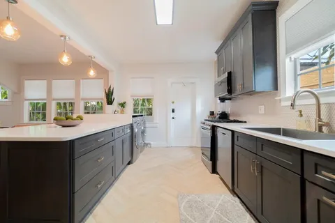 a kitchen with kitchen island granite countertop a sink counter top space appliances and cabinets