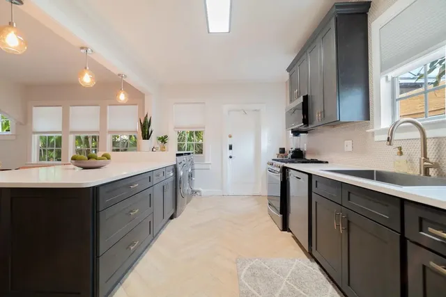 a kitchen with kitchen island granite countertop a sink counter top space appliances and cabinets